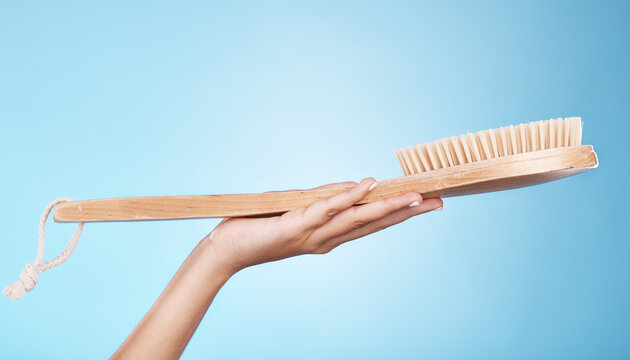 Woman, shower or bath hand brush for cleaning, hygiene and beauty grooming marketing. Model holding spa scrub treatment tool on blue studio background with mockup for cosmetic product.