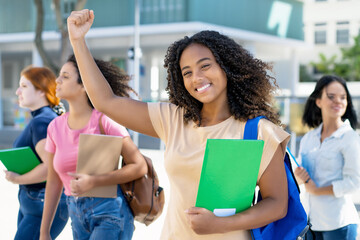Cheering black female student with group of latin american and caucasian young adults