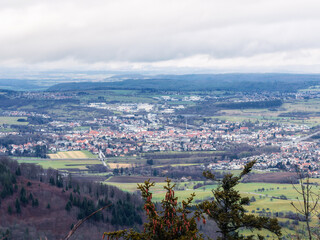 Ausblick vom Zeller Horn in Albstadt auf den kegelförmigen Zollerberg mit Burg Hohenzollern, das Tal mit Hechingen, Wessingen und Boll und am Horizont die Schwäbische Alb