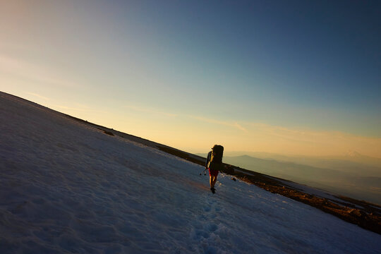A backpacker crosses a snowfield on Mt Hood while hiking the Timberline trail.