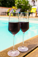 Two glasses of red wine near the swimming pool, chill out area near swimming pool, summer vacations. 
