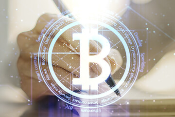 Creative Bitcoin concept with woman hand writing in diary on background. Double exposure