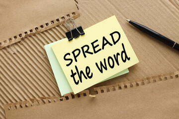 Spread the word. text on yellow sticky note on brown background. Business concept.