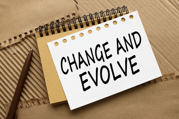 text on notebook pages on brown background. CHANGE AND EVOLVE, business success concept