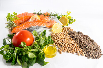Plate of fresh raw salmon fillets with herbs, parsley, lemon and legumes, chickpeas, lentils, balanced diet on a white background.