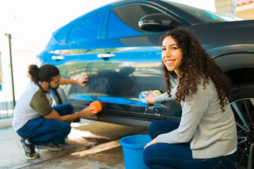 Smiling couple cleaning the car in the garage