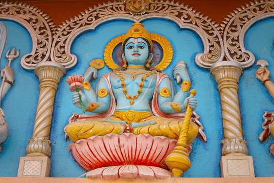 Supreme God Vishnu sits on a lotus with a mace. Image of God on the wall of a Hindu temple in Mayapur, India.