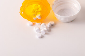 white pills coming out of prescription pill bottle isolated on white background with room for copy or print.