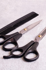 Barber scissors and comb on gray background