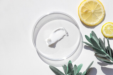 natural face cream in petri dish on a white table and plant branches - obrazy, fototapety, plakaty