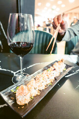 Sushi dish in a restaurant with hands with chopsticks out of focus