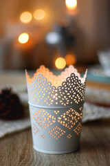 Cup of tea, books, tablet, bowl of cookies, various spices, pine cones and lit candles. Hygge at home. Selective focus.