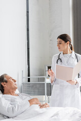 Doctor with paper folder talking to elderly patient in clinic.