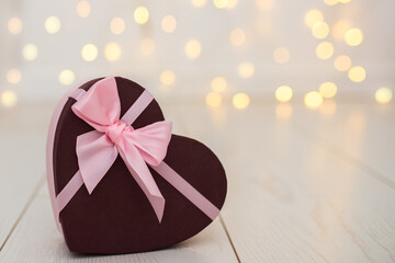 gift box in the shape of a heart with a pink bow on a background of defocused lights. Valentine's day concept. valentine's day card