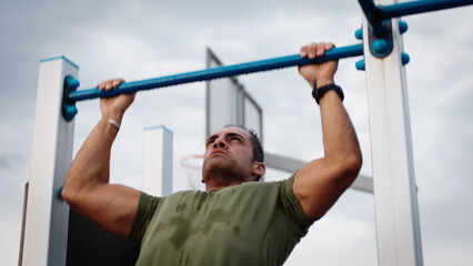 Man is doing pull ups exercises on horizontal bar