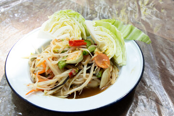 Thai papaya salad (Somtum) in white plate on wooden table