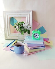 Back to school, alarm clock, apple tree flowers bouquet, stack of books, cup of tea, and stationery on the table, education, vacation time