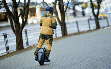 Man riding fast on unicycle through city street. Stylish man in safety gear and protective helmet riding electric self balancing monowheel outdoor. Personal mobility electric transport, single wheel © Tricky Shark