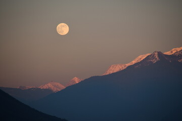 Plein lune au dessus des montagnes au coucher du soleil, dans les Alpes, en hiver © Ornella
