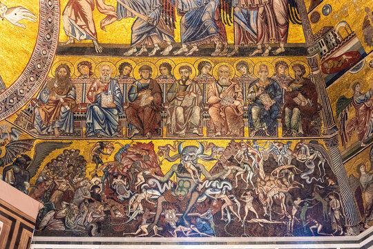 Close-up on parts of religious mosaic decorating the ceiling of catholic church in Florence showing a line of saints standing above a grotesque scene in hell