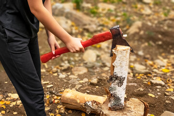 Female strong hands chop firewood with axe for bonfire. Powerful ax blow. Survival on camping trip....