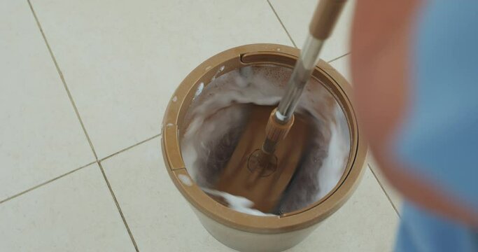 Slow motion of woman holding a mop spinning in the bucket