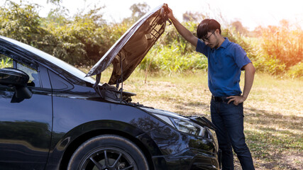 The car broke down, problem under the hood, the driver serious. man looks at the engine of the car. The driver is the man near the broken car. Man having car troubles - broken down on the side.