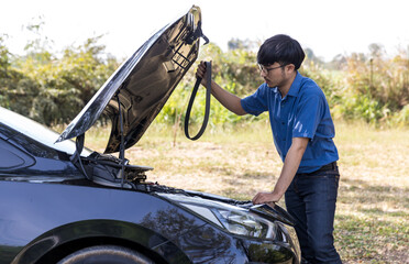 The car broke down, problem under the hood, the driver serious. man looks at the engine of the car. The driver is the man near the broken car. Man having car troubles - broken down on the side.