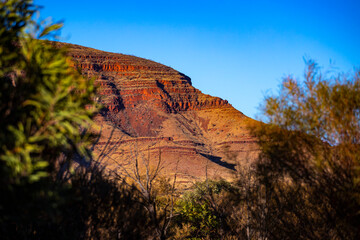 Sunrise over mighty mountains in karijini national park in western australia; Australian outback with red rocks, distinctive trees and mountains in the background