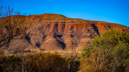 Sunrise over mighty mountains in karijini national park in western australia; Australian outback with red rocks, distinctive trees and mountains in the background