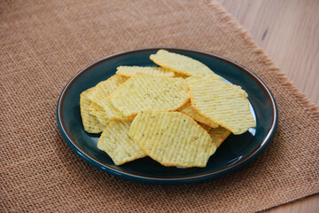 Yellow salty fluted chips in a decorative plate