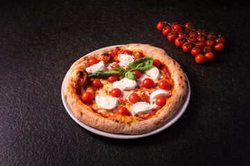 pizza with buffalo mozzarella and cherry tomatoes on a dark background