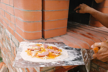 Raw pizza lies on a shovel before being cooked in a professional brick oven