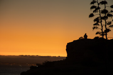 Half body silhouette of a girl on top of a mountain while watching the sunset, Algarve, Portugal