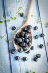Fresh juicy blueberries with green leaves on a blue background. Healthy berry, organic food, vitamin, blue food.