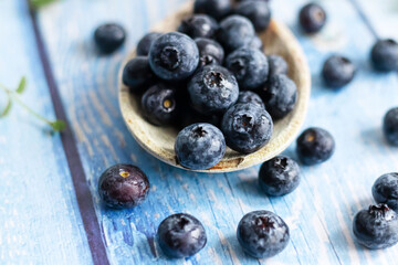 Fresh juicy blueberries with green leaves on a blue background. Healthy berry, organic food, vitamin, blue food.