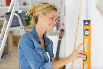 woman leaning a spirit level on the wall