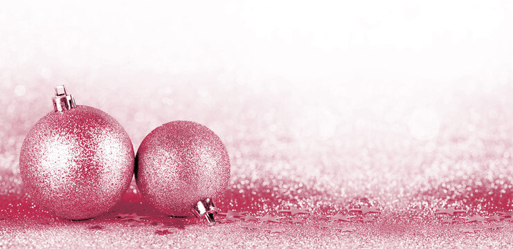 Christmas boubles on silver glitter with sparkling defocused lights on background. Viva Magenta color of the year 2023