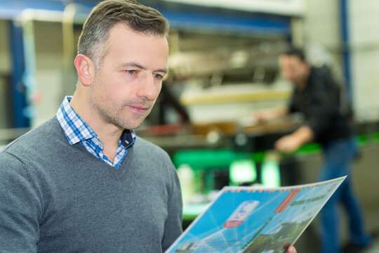 printer checking a print run at table