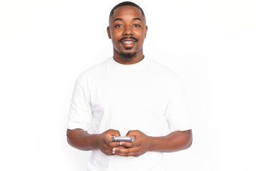 Joyful young man using smartphone. Male African American model with brown eyes, short haircut and beard in white T-shirt holding smartphone in his hands. Modern technology concept