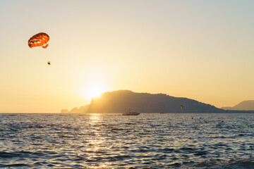 People Parasailing Over Sea Against Sky During Sunset