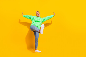 Fototapeta na wymiar Full body length photo of young overjoyed positive girl wear stylish hoodie with denim jeans new sneakers dance isolated on yellow color background