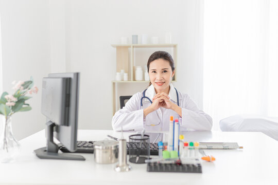 Asian Female Doctor Rest In Her Office, She Reading And Order Treatment Process On Patient Chart, She Sitting And Smile In Hospital