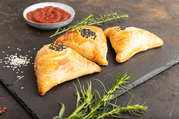 Homemade asian pastry samosa on black. side view.