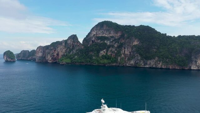 Towering Limestone stalled by shoreline winding around Ko Phi Phi Don Island Paradise, Thailand - Aerial Fly-over shot