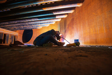 Welding male worker metal is part of machinery plate tank beam pipe construction flash spark inside...