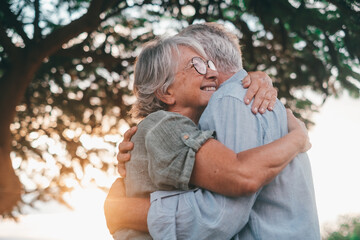 Fototapeta premium Head shot close up portrait happy grey haired middle aged woman snuggling to smiling older husband, enjoying tender moment at park. Bonding loving old family couple embracing, feeling happiness..