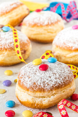 Carnival powdered sugar raised donuts with paper streamers, confetti and chocolate beans, vertical