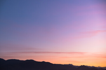 Purple silhouettes of mountains with aerial perspective against the background of the sunset sky....