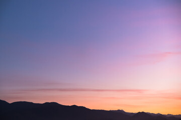 Fototapeta premium Purple silhouettes of mountains with aerial perspective against the background of the sunset sky. blue purple pink red orange yellow gradient